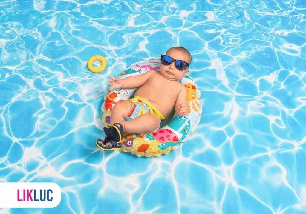 Bebê de óculos escuro deitado numa boia em uma piscina