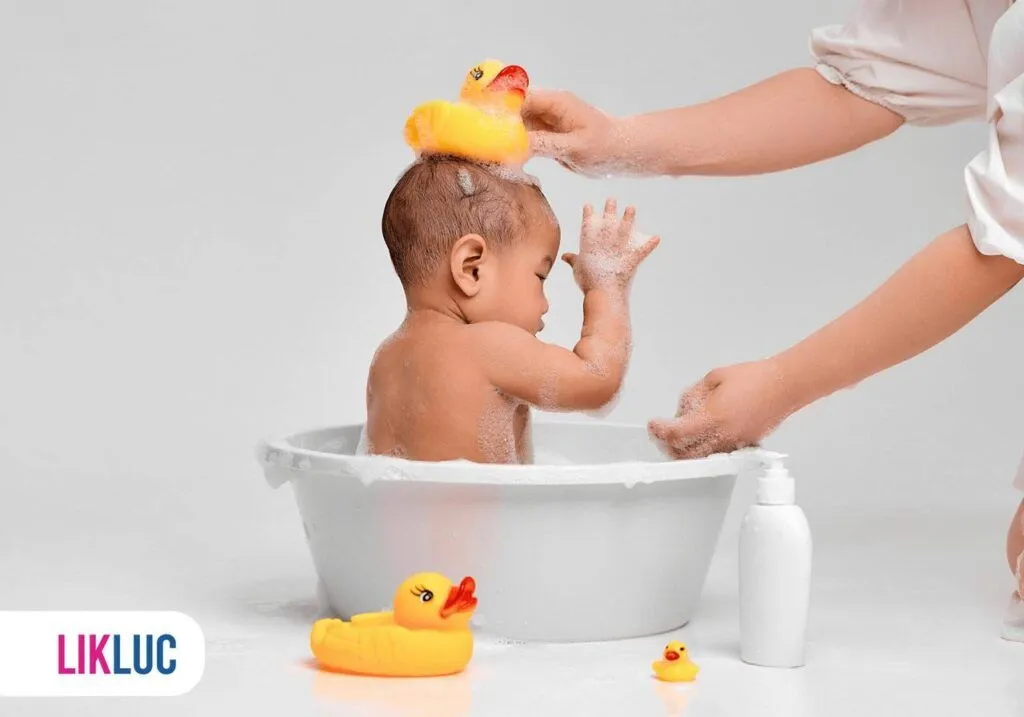 Bebê tomando banho na banheira com vários brinquedos de patihos