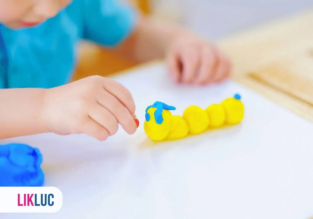 vista de cima de uma criança fazendo uma centopéia com bolinhas de massa de modelar amarela