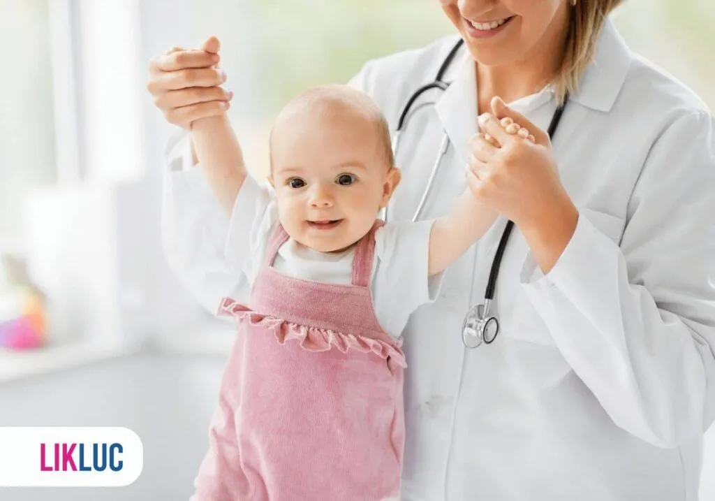 bebe sorrindo com as mãozinhas para cima, sendo segurada por sua pediatra