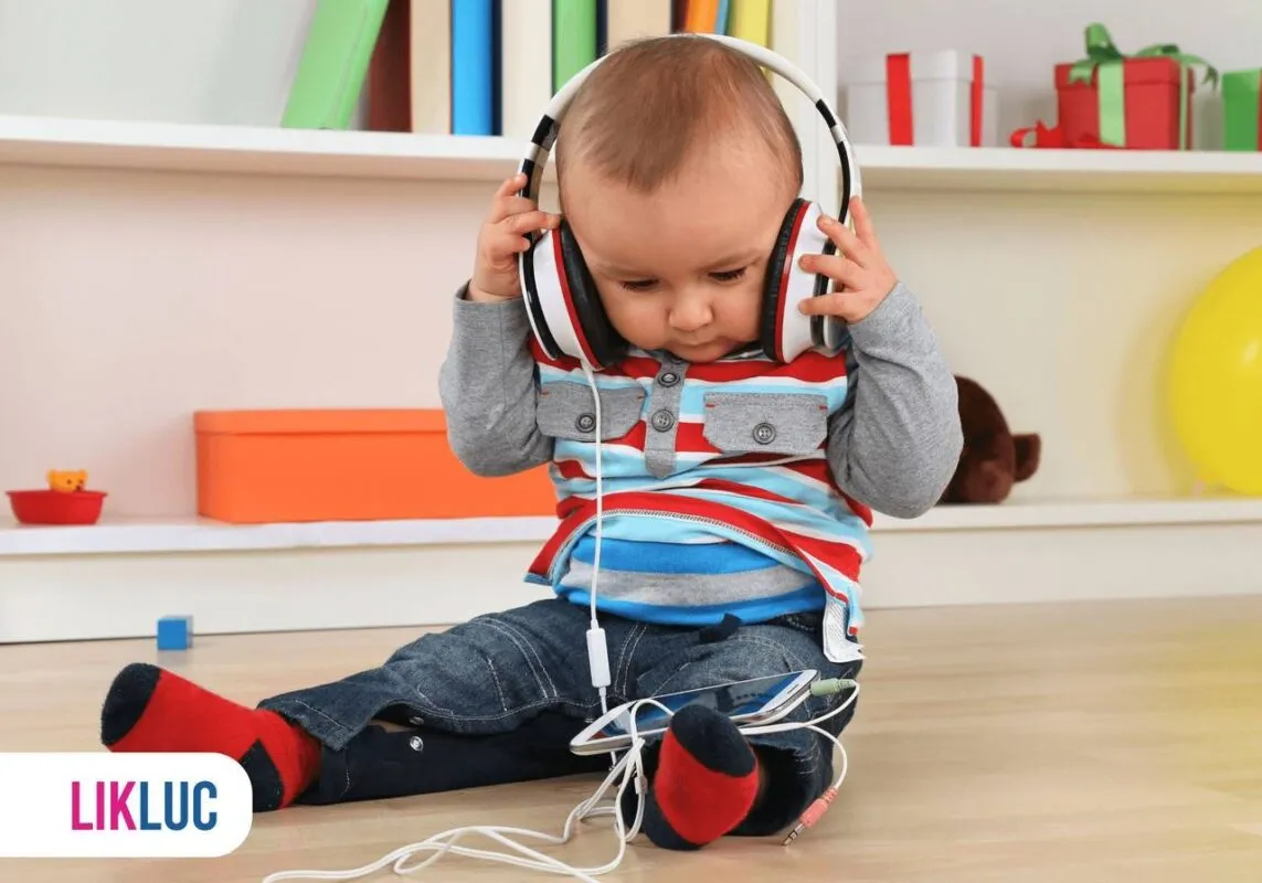 Bebê sentado e segurando fone de ouvido escutando música
