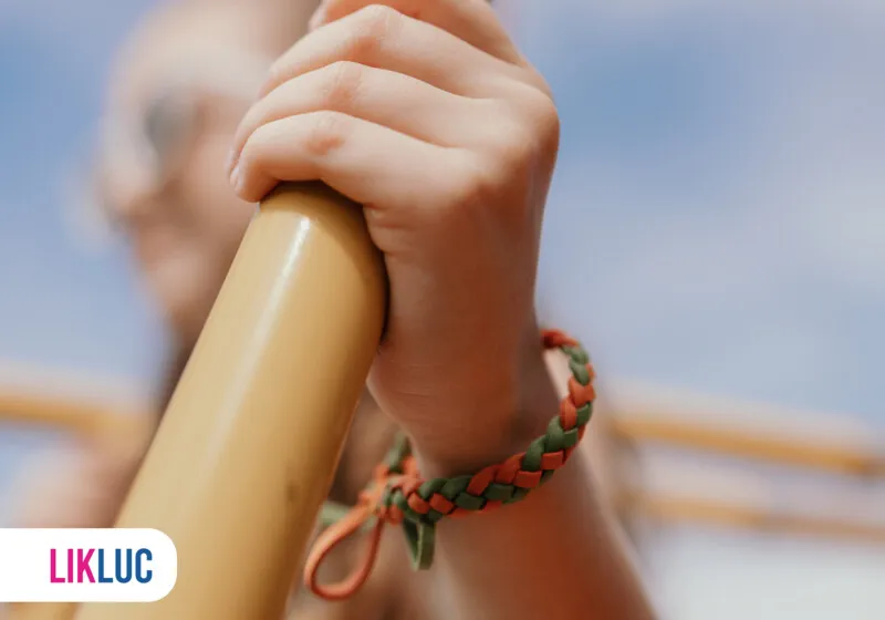mão segurando uma barra com pulseira colorida de citronela