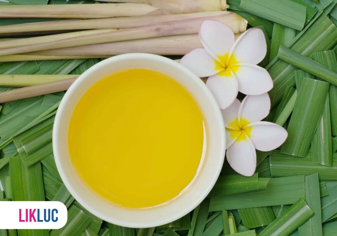 Óleo aromático de citronela ao lado de flores e folhas verdes