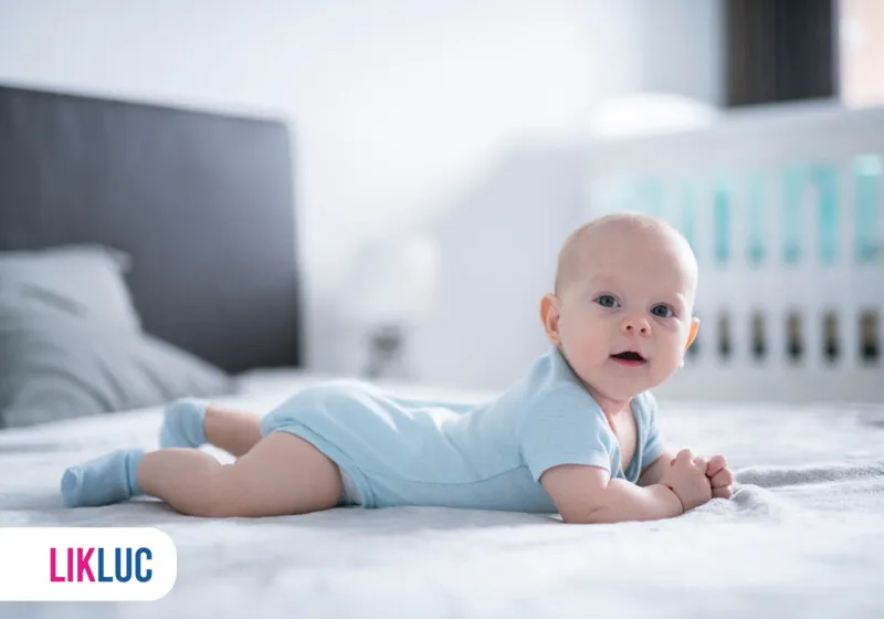 Bebê deitado de barriga para baixo em um berço.
