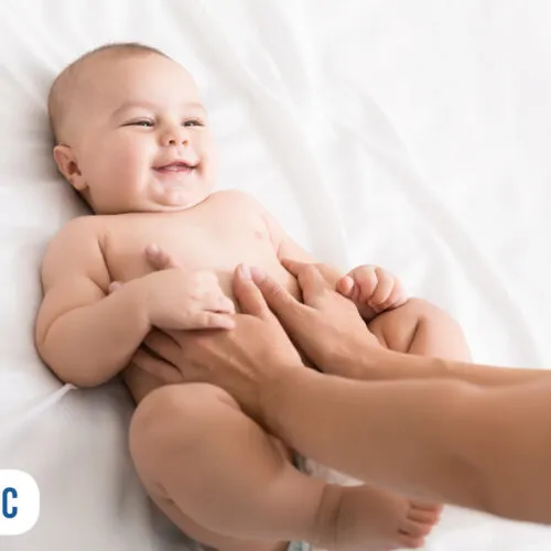 Bebê sorrindo durante carinho em cama branca