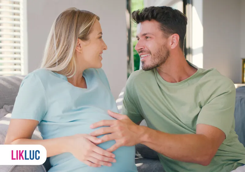 Casal sorridente em momento íntimo de expectativa na gravidez